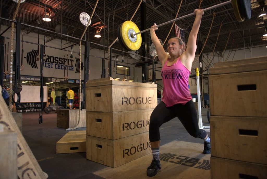 Woman learning how to Jerk at a CrossFit gym